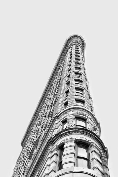 low angle view of the flatiron building, a historic triangular shaped skyscraper in new york city, against a plain, light gray sky. the image highlights the buildings ornate architectural details. small business loans SBA Loans for Small Businesses Business Term Loans