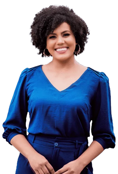 a woman with curly hair smiles, wearing hoop earrings and a bright blue blouse with long sleeves and matching pants, standing against a neutral background. small business loans