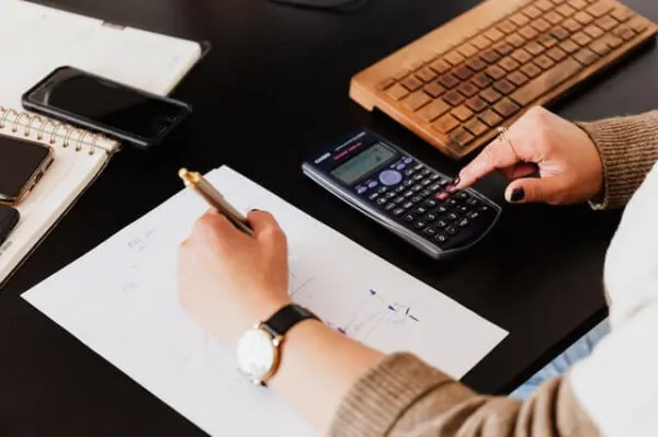 crop woman using calculator and taking notes on paper How SBA loans work How SBA loans work