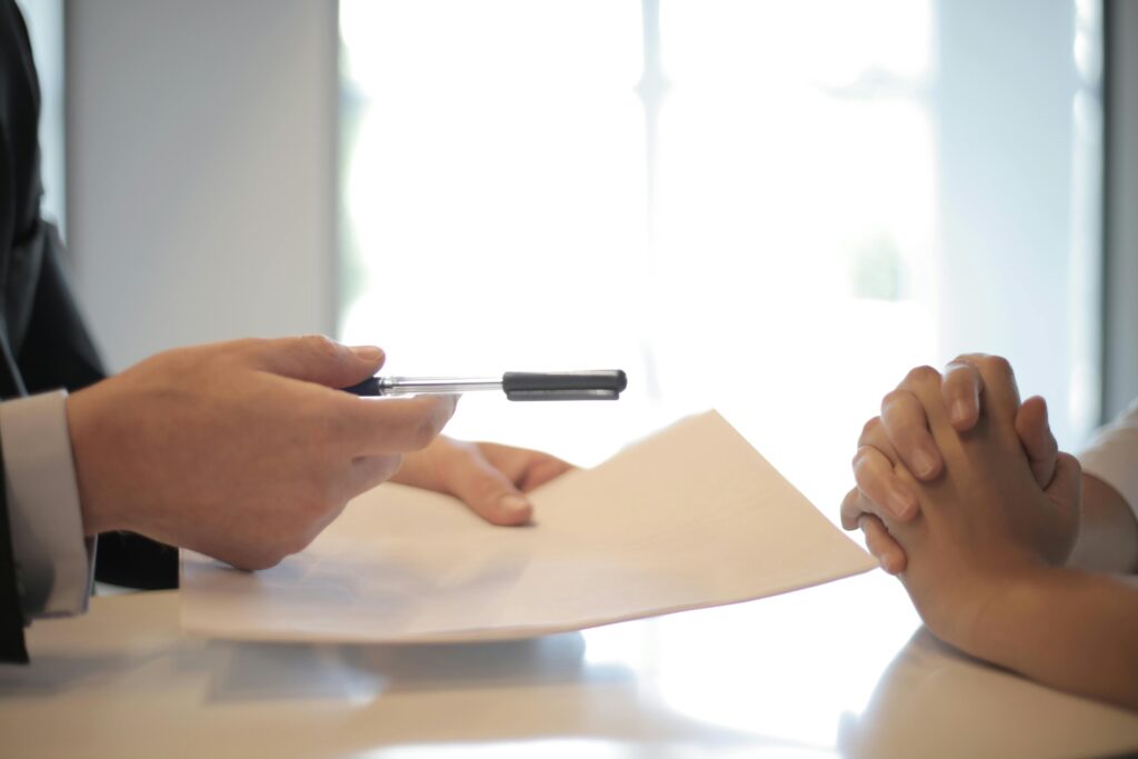 Close-up of a contract signing with hands over documents. Professional business interaction. SBA Loan Application Step by Step Process
