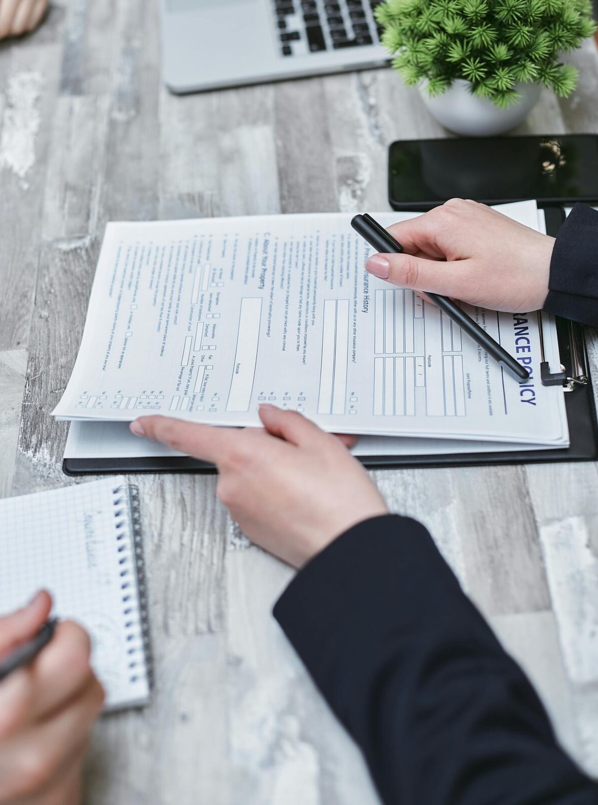 Close-up of hands analyzing insurance policy paperwork with pen on table. SBA Loan Application Step by Step Process